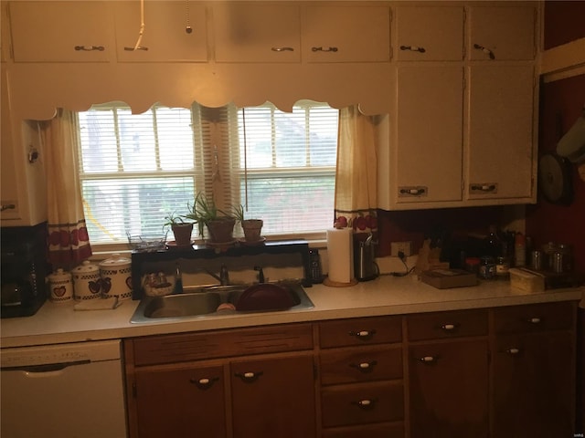 kitchen with light countertops, white dishwasher, and a sink