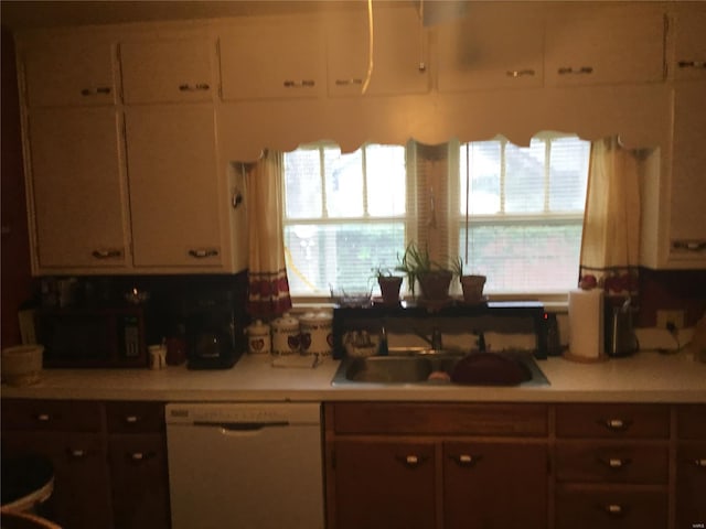 kitchen featuring light countertops, white dishwasher, white cabinetry, and a sink