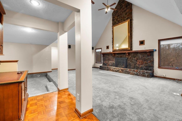 interior space with a ceiling fan, a textured ceiling, a fireplace, baseboards, and light carpet