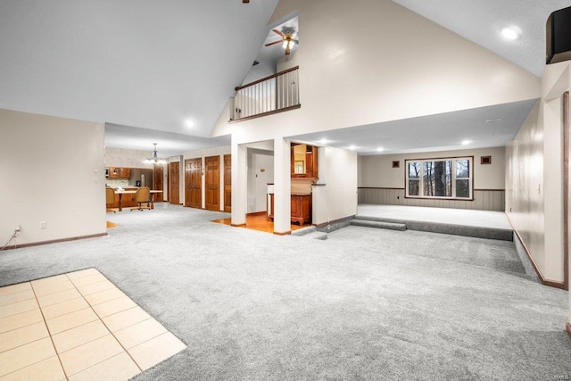 unfurnished living room featuring baseboards, high vaulted ceiling, recessed lighting, carpet flooring, and ceiling fan with notable chandelier