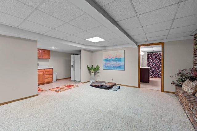 interior space featuring baseboards, a paneled ceiling, and light carpet