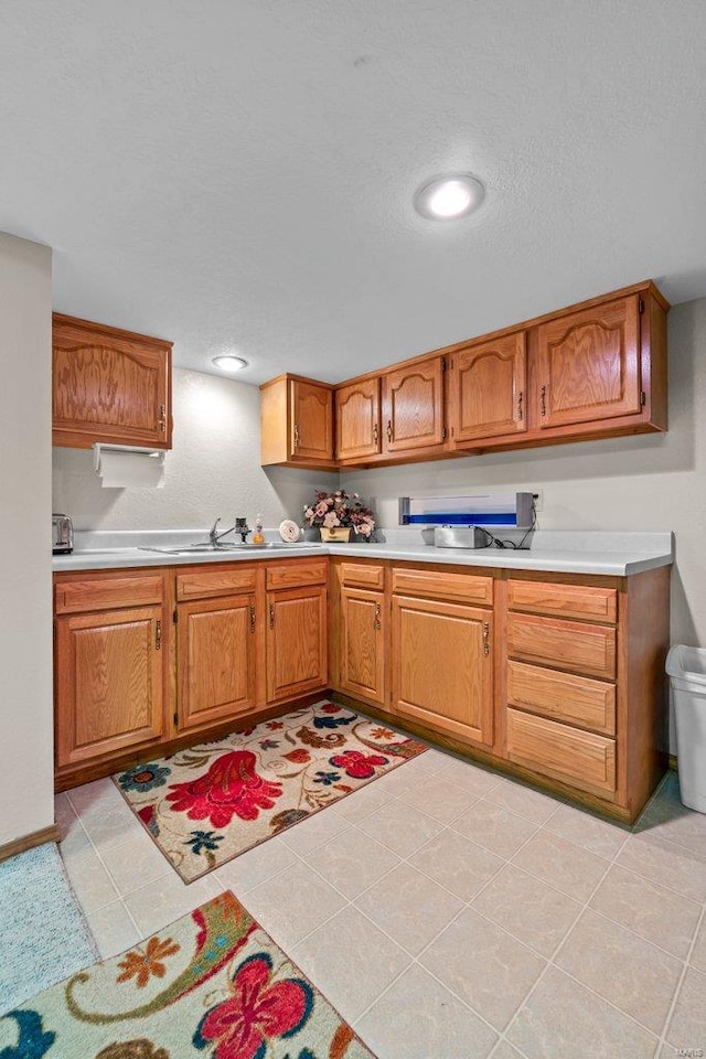 kitchen featuring light countertops, brown cabinetry, and a sink