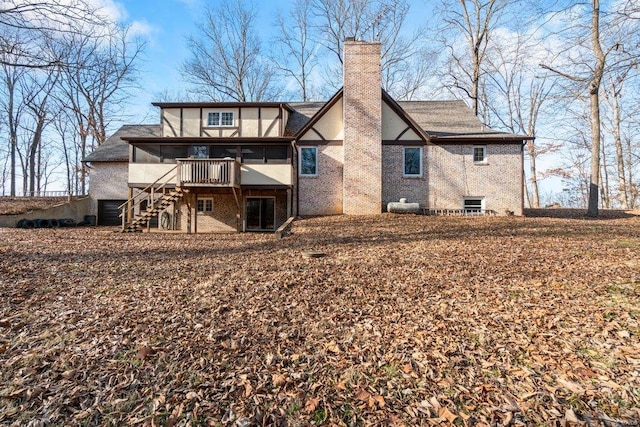 rear view of house with stairs, brick siding, stucco siding, a sunroom, and a chimney