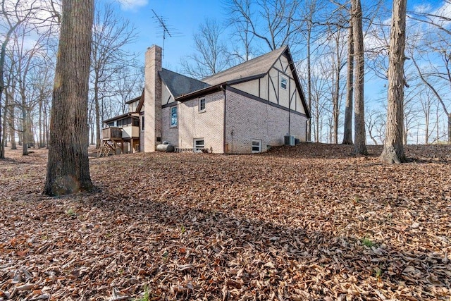 view of home's exterior featuring central air condition unit, brick siding, and a chimney