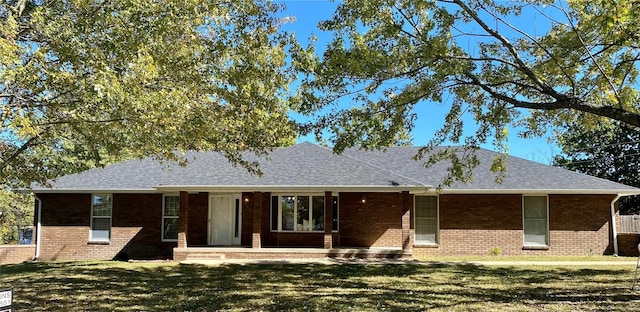 view of front of home with roof with shingles, a front lawn, and brick siding