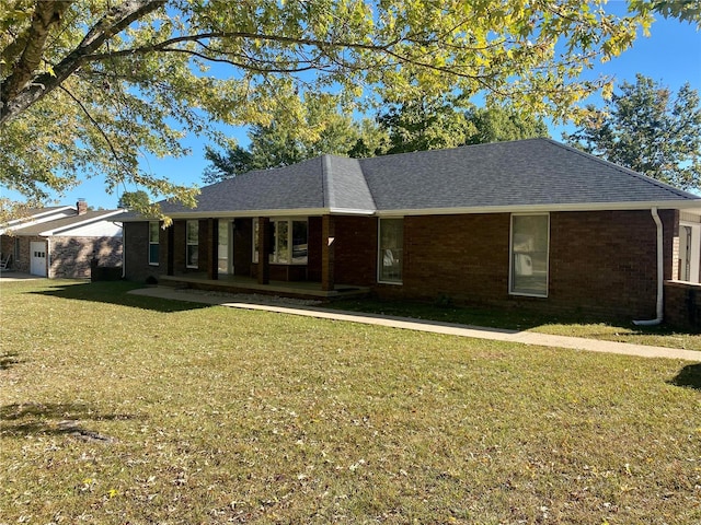 ranch-style house featuring an attached garage, a front lawn, roof with shingles, and brick siding