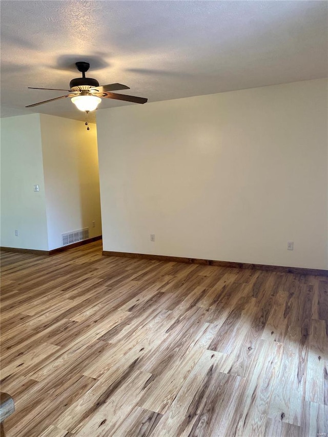 unfurnished room with visible vents, wood finished floors, baseboards, a textured ceiling, and a ceiling fan