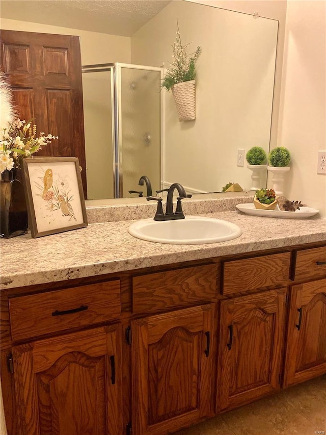 bathroom featuring a textured ceiling, a shower stall, and vanity