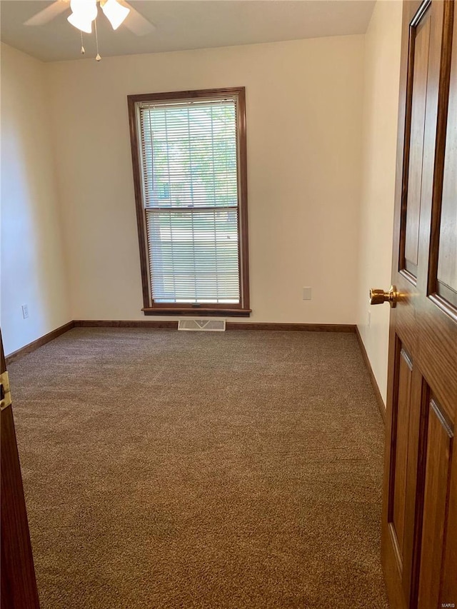 unfurnished room with baseboards, ceiling fan, carpet, and visible vents