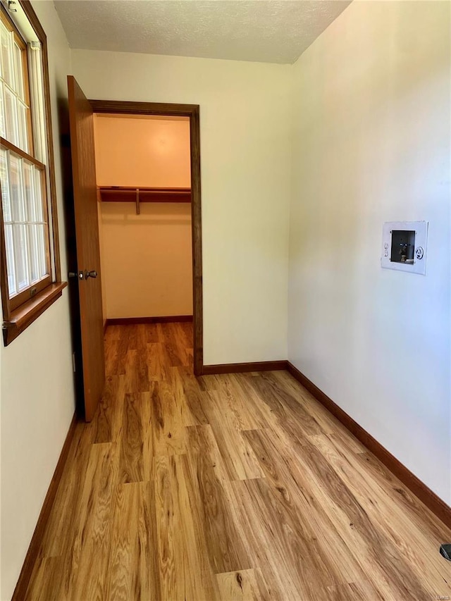 unfurnished bedroom featuring light wood-style floors, baseboards, a spacious closet, and a closet