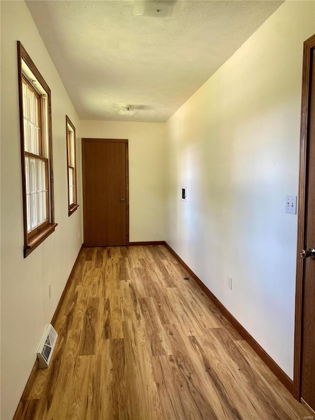 hall featuring baseboards, visible vents, and wood finished floors