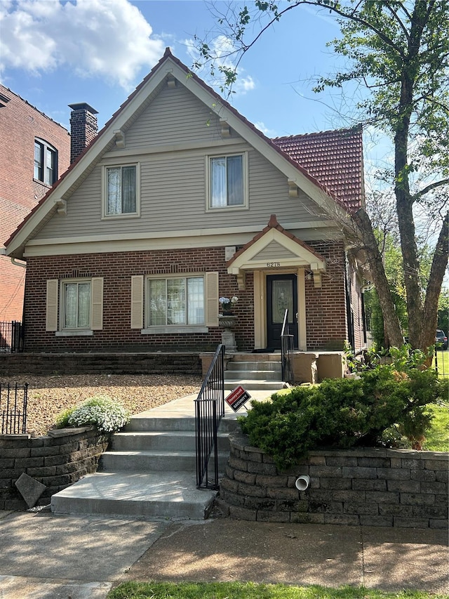 view of front of property featuring brick siding and a chimney