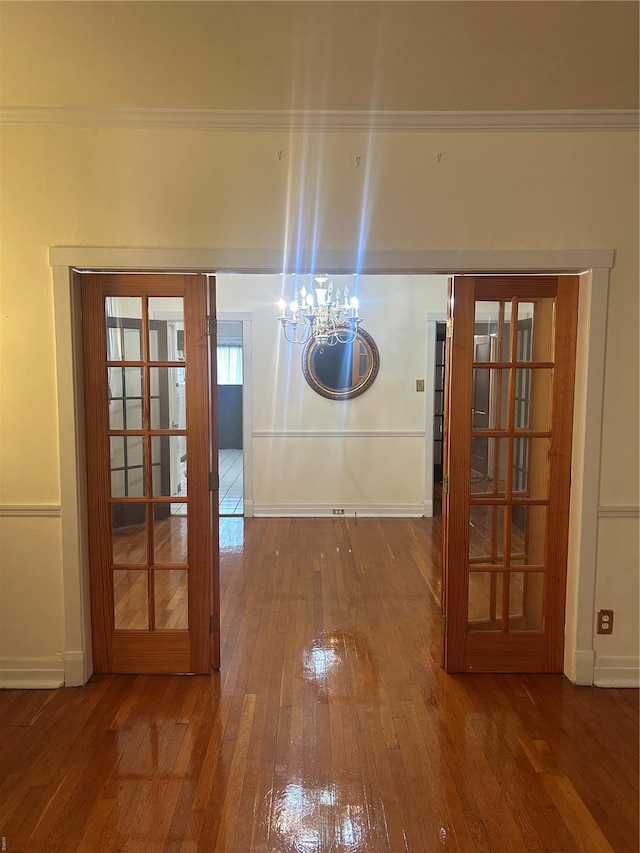 hall with an inviting chandelier, baseboards, and wood-type flooring