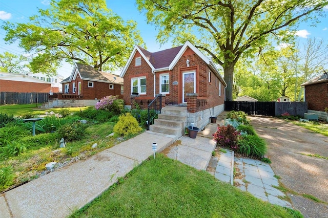 bungalow-style home with brick siding and fence