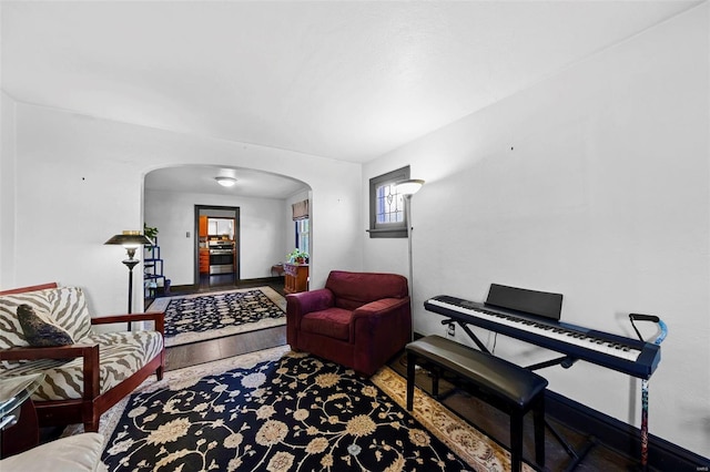 living room with arched walkways, baseboards, and wood finished floors