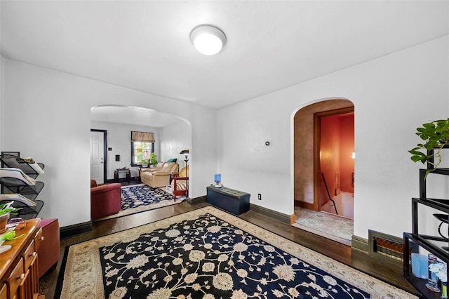 foyer entrance featuring arched walkways, baseboards, and wood finished floors