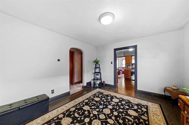 foyer with baseboards, arched walkways, and wood finished floors