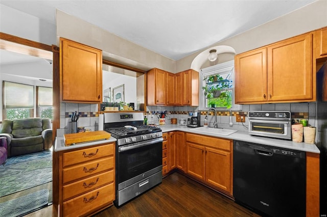 kitchen featuring stainless steel range with gas stovetop, dark wood finished floors, dishwasher, a sink, and light countertops