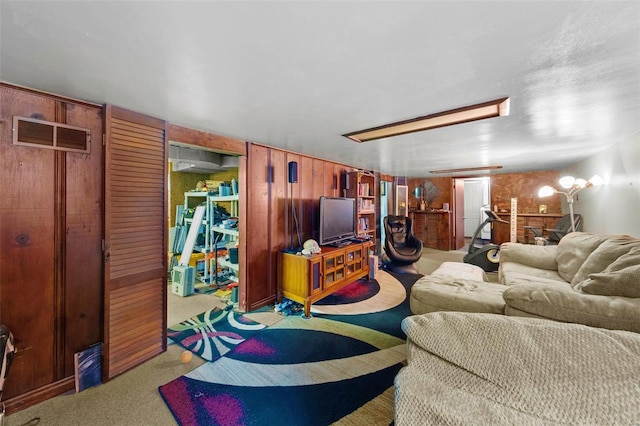 living room with wooden walls, carpet floors, and visible vents