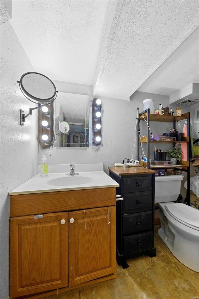 bathroom featuring toilet, a textured ceiling, and vanity