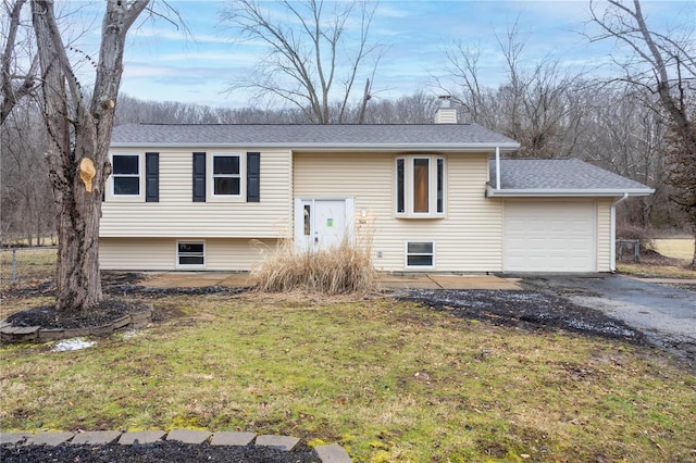 raised ranch with roof with shingles, a garage, a front yard, a chimney, and driveway