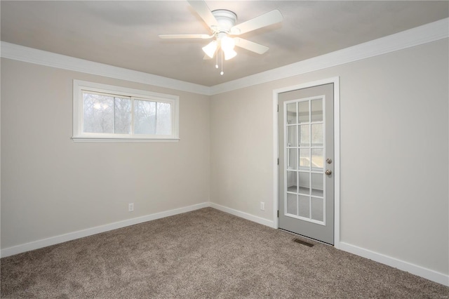 carpeted spare room with crown molding, ceiling fan, visible vents, and baseboards