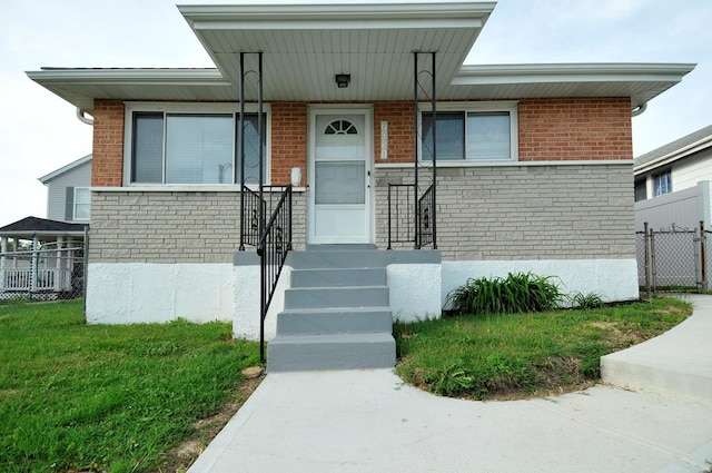 view of front facade with fence, a front lawn, and brick siding