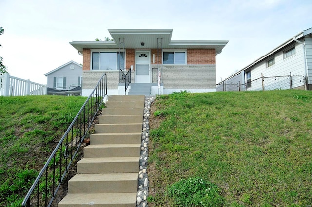 view of front of house featuring stairway, brick siding, fence, and a front yard