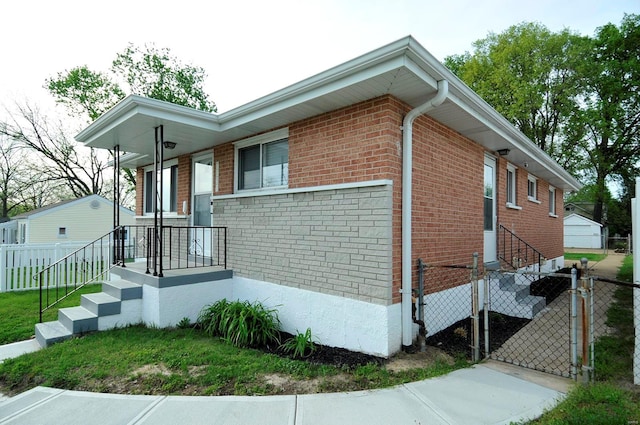 view of side of home with brick siding, a gate, and fence
