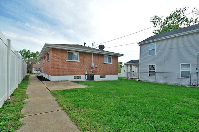 back of property with fence, central AC, brick siding, a patio, and a yard