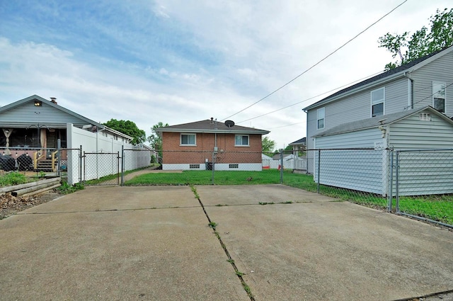 back of property with fence, a gate, and a lawn