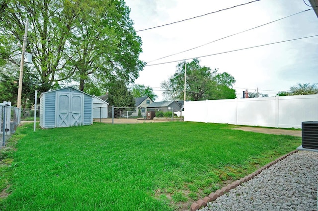 view of yard with central AC unit, a fenced backyard, an outbuilding, and a shed