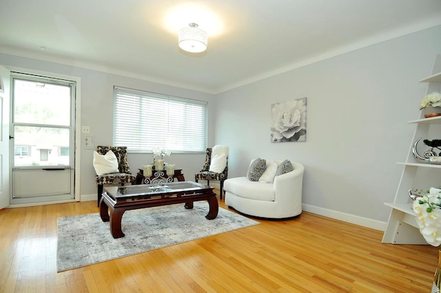living area with a healthy amount of sunlight, baseboards, and light wood-type flooring