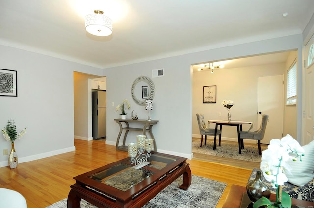 living area with visible vents, light wood finished floors, baseboards, and a chandelier