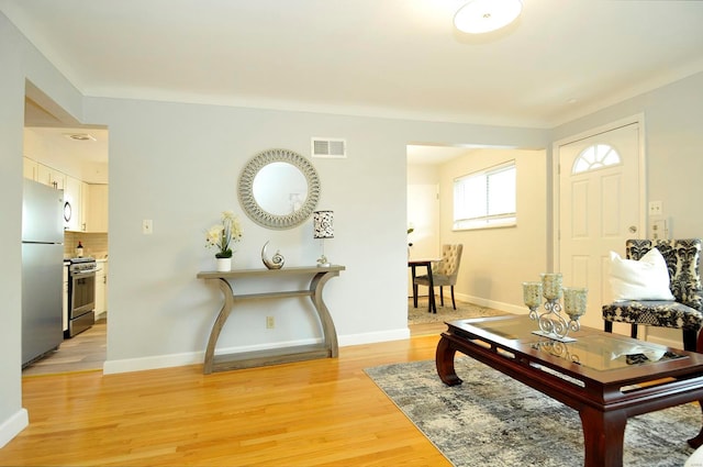 living room with baseboards, light wood-type flooring, and visible vents