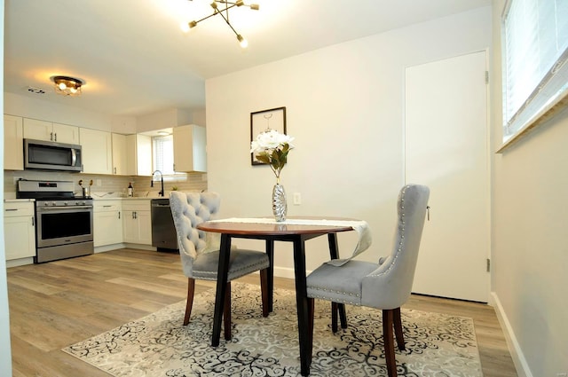 dining area featuring baseboards, an inviting chandelier, and light wood finished floors