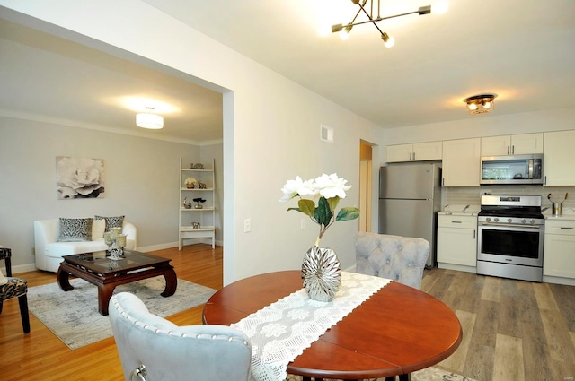 dining room with baseboards, an inviting chandelier, visible vents, and light wood-style floors