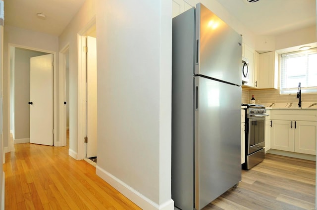 interior space with baseboards, a sink, and light wood-style flooring