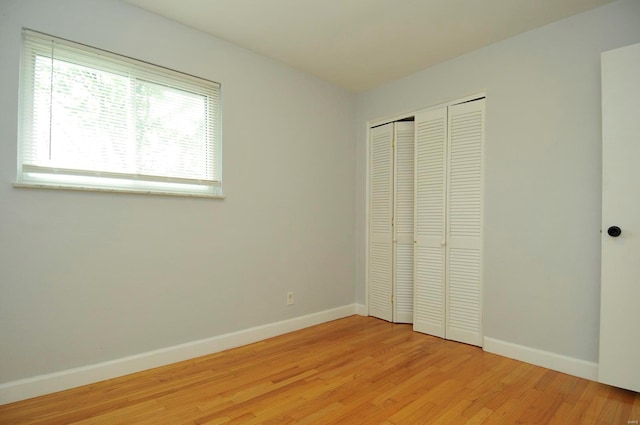 unfurnished bedroom with baseboards, a closet, and light wood-type flooring