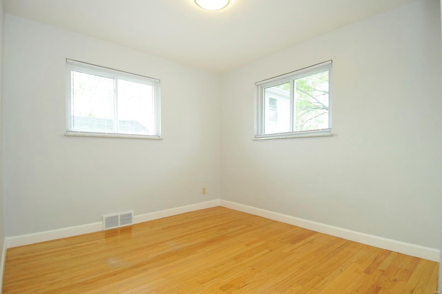 spare room with visible vents, baseboards, and light wood finished floors