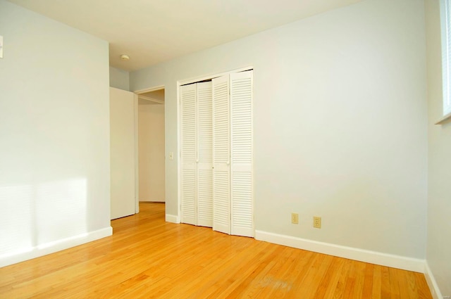 unfurnished bedroom with baseboards, light wood finished floors, and a closet