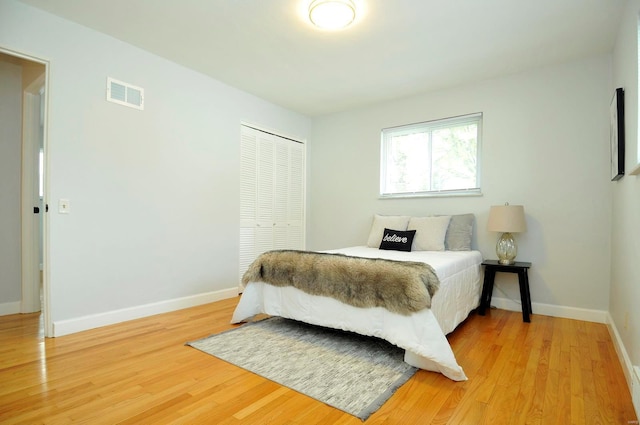 bedroom featuring baseboards, a closet, light wood-style flooring, and visible vents