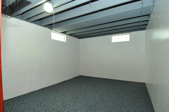 basement with a healthy amount of sunlight and dark carpet