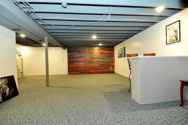 finished below grade area featuring carpet flooring and brick wall