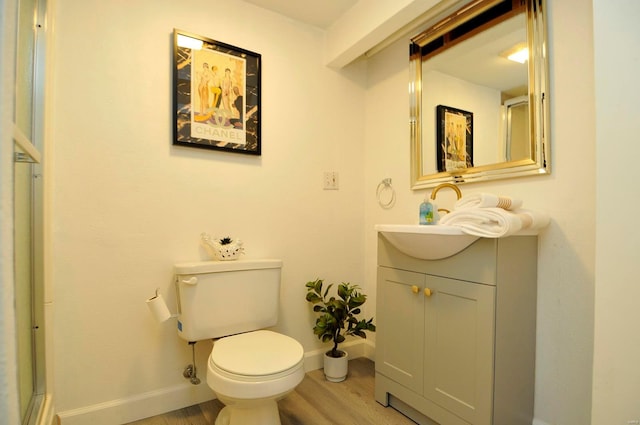 bathroom featuring vanity, baseboards, wood finished floors, and toilet