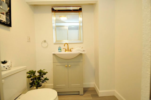 bathroom featuring vanity, baseboards, wood finished floors, and toilet