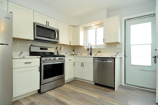 kitchen featuring light countertops, white cabinetry, tasteful backsplash, a sink, and appliances with stainless steel finishes