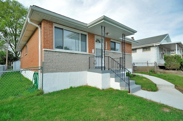 view of front of house featuring brick siding, fence, and a front lawn