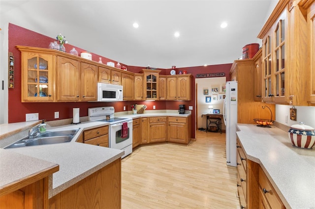 kitchen featuring a sink, white appliances, light countertops, and glass insert cabinets