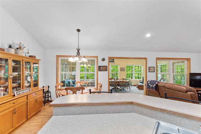 kitchen with light wood finished floors, open floor plan, pendant lighting, a notable chandelier, and light countertops